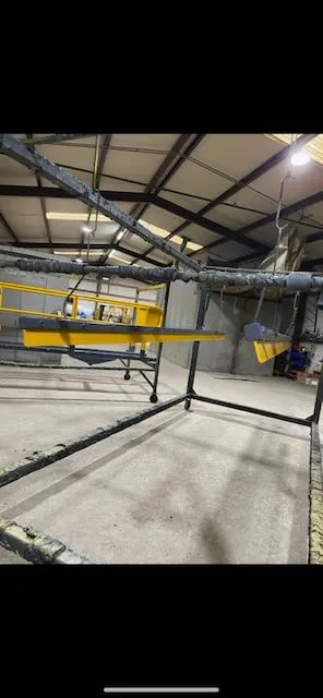 Yellow frame assembly on rotating stand in workshop